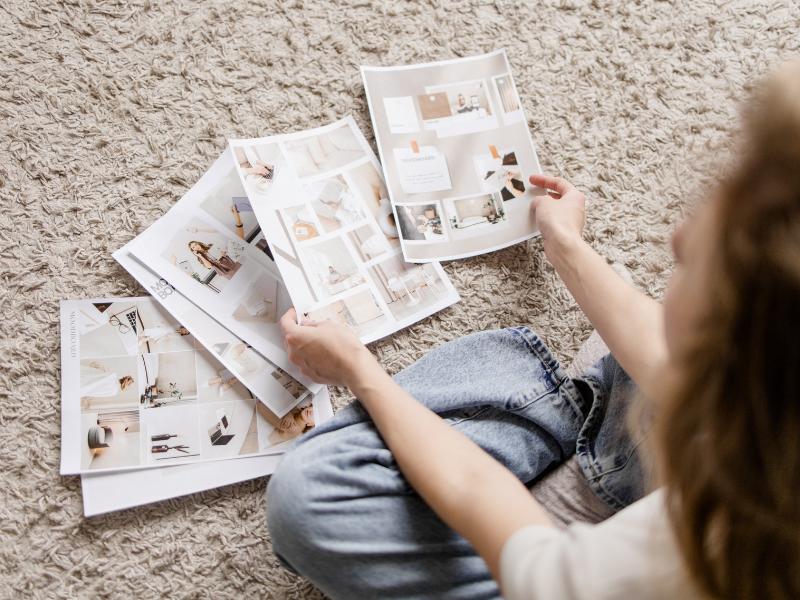 Foto einer Frau auf einen beigen Teppich, die verschiedene Fotos und Branding Elemente ordnet für ein Branding, dass mehr Kunden gewinnt.