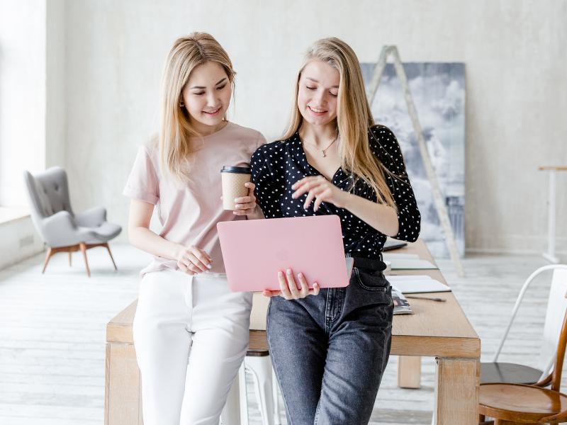 Dein Branding - Der Schlüssel zu mehr Kunden 1 Foto mit zwei blonden Frauen, die in einen rosa Laptop schauen. Kundengewinnung im Online Business durch professionelles Brand Design.