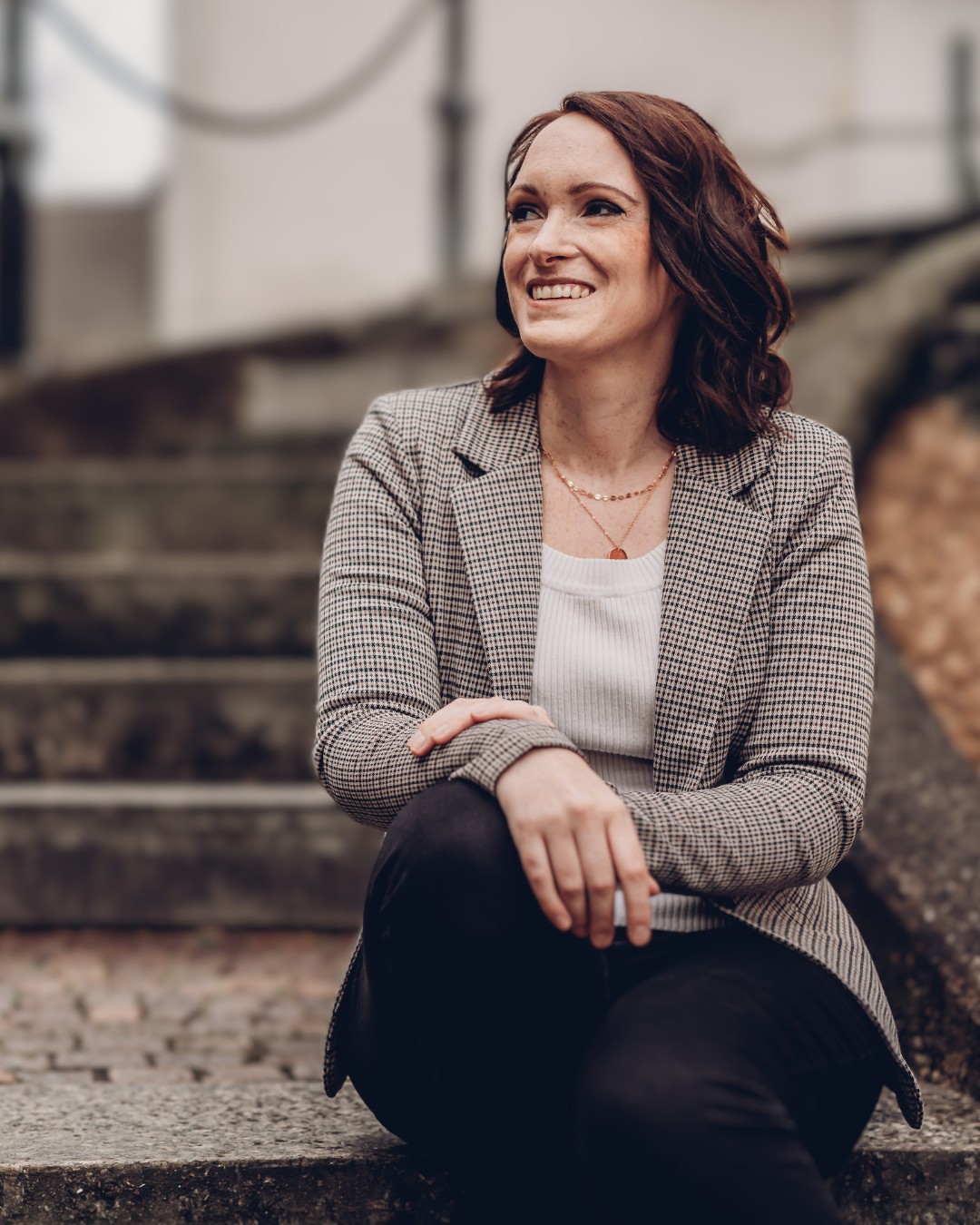 Calico Sky Studio About Me Brünette Frau mit Business-Blazer sitzt auf Treppe. Header-Bereich Calico Sky Studio Webdesign & Branding für Kreative, Coaches und Dienstleister