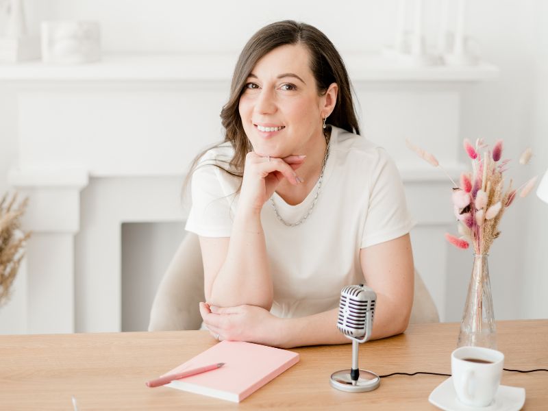Marketing ohne Druck - die 6 besten Methoden 2 Frau im cozy Home office ind weiß und rose Tönen mit Podcast Mikrofon. Longterm Content für Marketing ohne Druck.