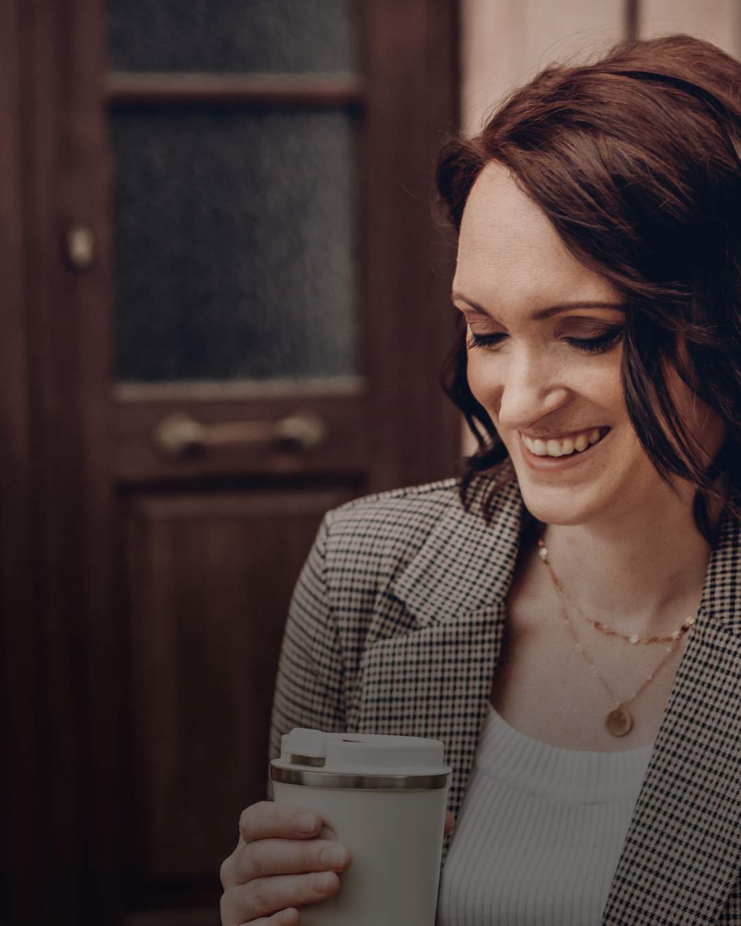 Brünette Frau in Blazer und Coffee To Go-Becher. About Calico Sky Studio, Boutique Design Studio für Premium Webdesign und Branding für Selbstständige.