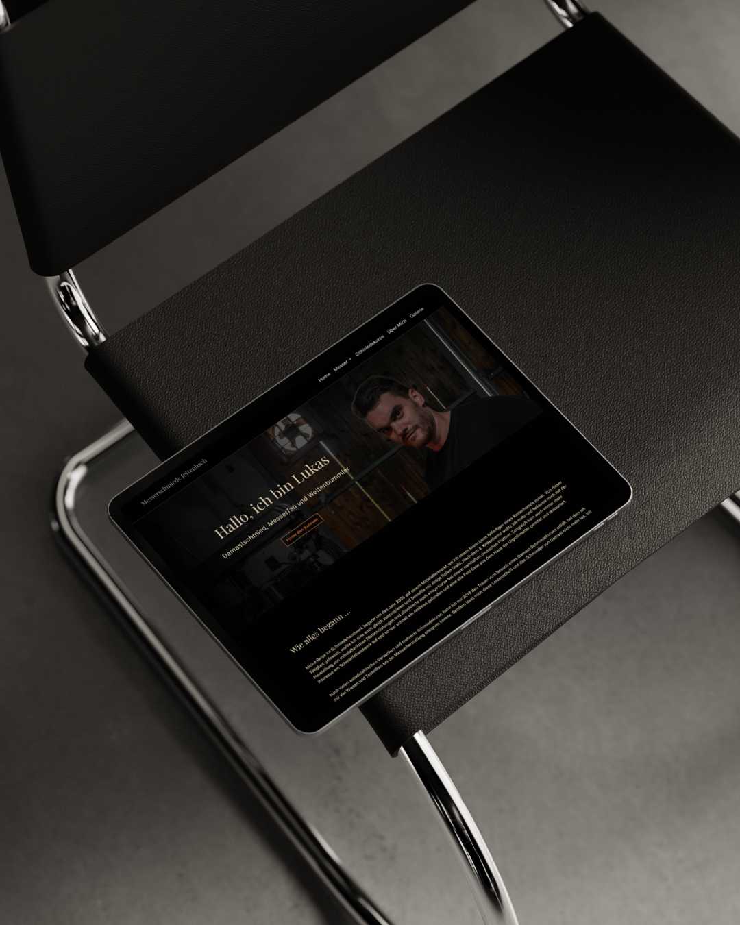 Calico Sky Studio - Happy Clients Designerstuhl aus schwarzem Leder und ein Tablet einer Website für einen Damastmesserschmied, Premium Webdesign by Calico Sky Studio.
