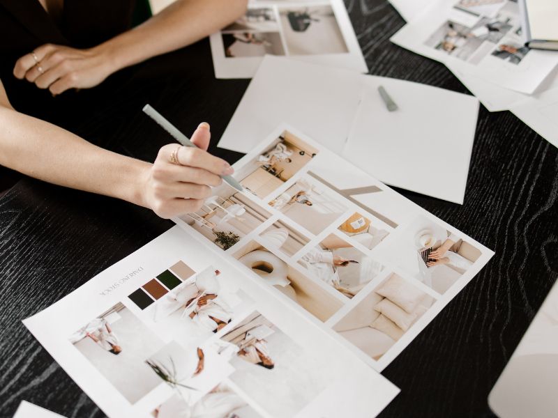 Moodboard erstellen für Brand Design. Frau in schwarzer Business-Kleidung stellt aus Fotos und Farbpaletten ein Moodboard zusammen.