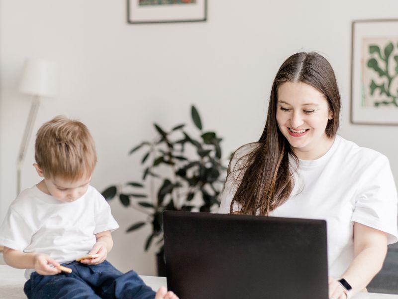 Nebenberuflich selbstständig machen - Vorteile & Nachteile 2 Braunhaarige Frau arbeitet von zuhause wegen Kinderbetreuung, nebenberuflich selbstständig machen in der Elternzeit