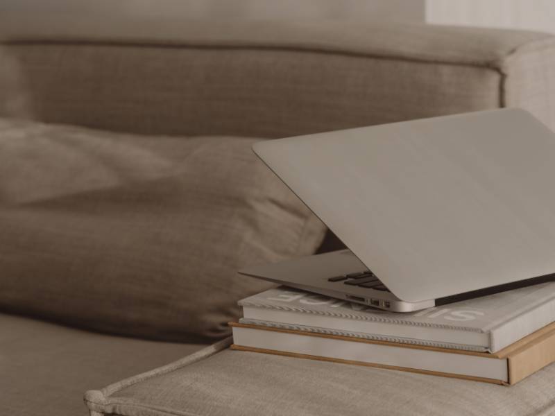 Laptop auf Bücherstapel und beiges Sofa. Zeigt Blogartikel über SEO-Tipps für Anfänger.