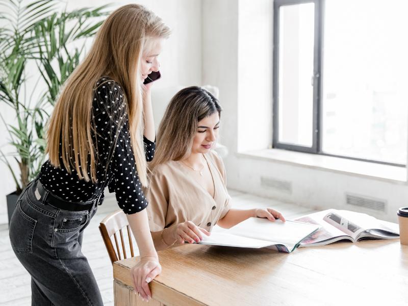 5 Webdesign-Fehler, die Selbstständige vermeiden sollten 2 Zwei Frauen in Marketing Agentur erarbeiten Kernmessage bzw. Elevator Pitch für Kleinunternehmen.