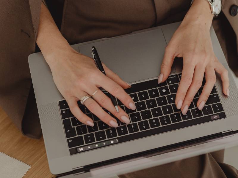 Frau an Laptop schreibt blogartikel über die nachteile von Website Baukasten.
