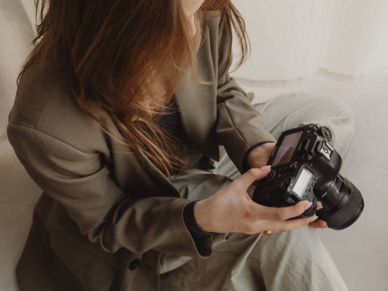 Frau in grünem Blazer hält eine Spiegelreflexkamera. Fotografin für Business Fotos. Blogartikel für Tipps für überzeugende Website-Fotos