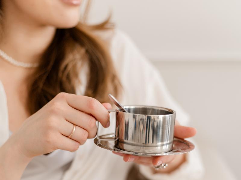 Anfänger-Tipps: Website Ladezeiten verbessern Frau in Business Dress mit silberner Tasse. Titelbild Blogartikel über Website Ladezeiten verbessern für Selbstständige - Tipps für Anfänger.