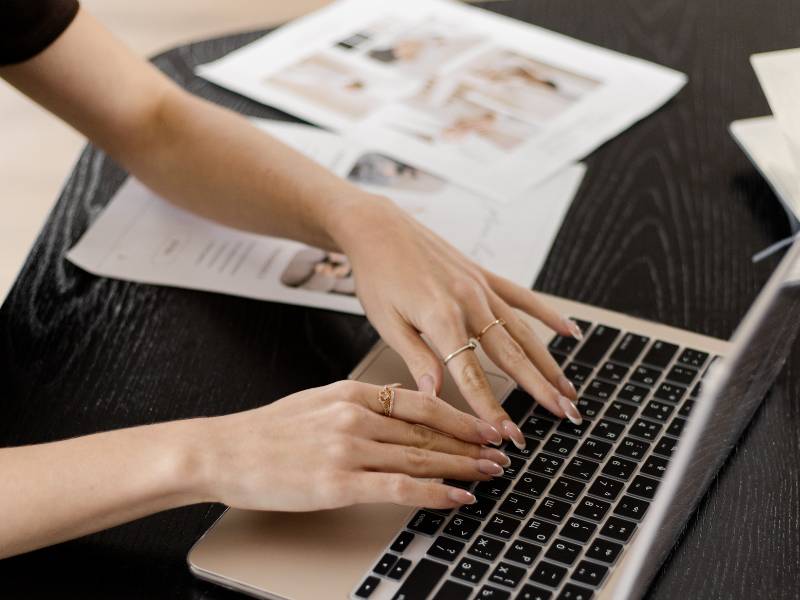 Frau mit Nagellack in rosé arbeitet remote am Laptop - Titelbild Blogartikel mit dem Thema Website oder Social Media - was brauchen Selbstständige wirklich